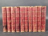 six old red books lined up in a row on a black surface
