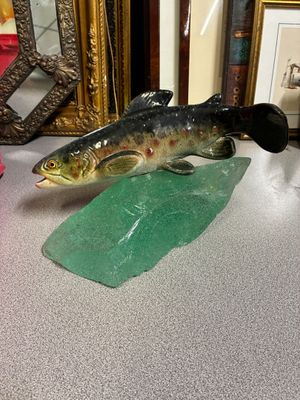 statue représentant un poisson assis sur une feuille verte, à côté d'un miroir