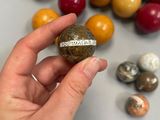 someone is holding a rock with a message on it in front of a pile of colorful rocks