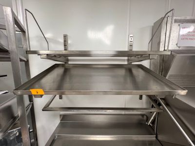 des étagères en acier inoxydable dans une cuisine professionnelle disposant d'un grand plan de travail
