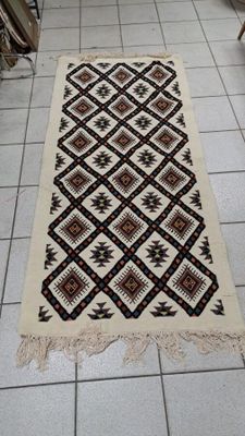 Un tapis à décor géomatrique et franges.