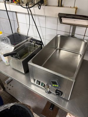 plan de travail en acier inoxydable équipé de deux friteuses dans une cuisine professionnelle