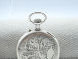 a silver pocket watch sitting on top of a white cloth