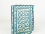an old blue book with gold and white designs sitting on a white surface