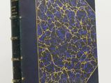 an old book with a blue cover sitting on top of a white table