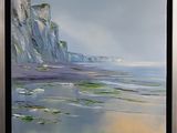 framed oil painting of a beach scene with a cliff in the background