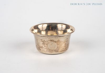 un petit bol en argent posé sur une surface blanche