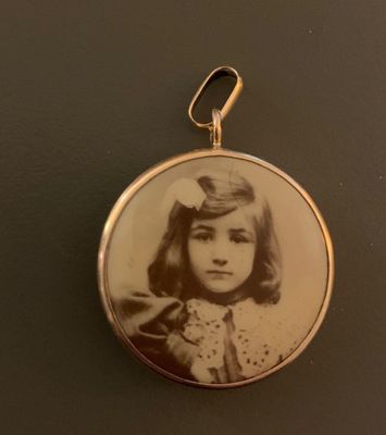 Une vieille photo représentant une jeune fille en robe est exposée dans un pendentif