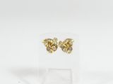 une paire de boucles d'oreilles en or et diamants posée sur un présentoir transparent