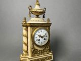 a gold clock with a vase on top of it