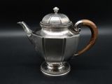 a silver teapot with a wooden handle on a black background