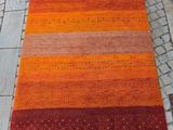 un tapis rayé orange et rouge posé sur un sol en briques