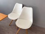 two white chairs sitting next to a table in a room