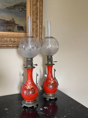 deux vases rouges posés sur une table noire, avec un tableau en arrière-plan