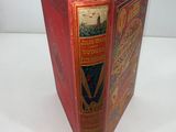 an old book with a red cover sitting on top of a white table