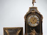 a clock with a statue on top of it next to a bench