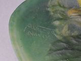 a green vase with a yellow flower on top of it