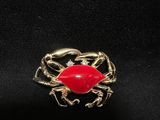 a gold ring with a red crab on it