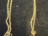 gold plated cross necklace with a chain that is attached to the back of it