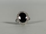 a black stone and diamond ring on a white surface