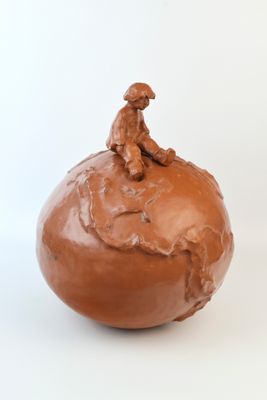 une sculpture en argile représentant un homme assis sur une pomme