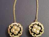 paire de boucles d'oreilles avec des perles et des chaînes en or sur un fond noir