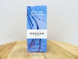 un flacon de parfum Rochas posé sur une table en bois