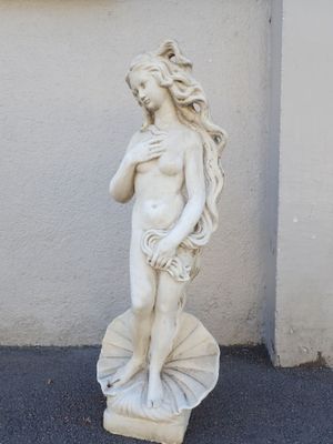 a statue of a woman holding a shell on the ground