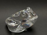 a clear glass frog figurine on a black surface