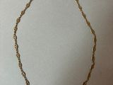 un collier en or représentant une corde torsadée sur fond blanc