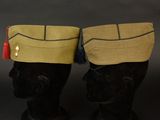 pair of military hats with tassels on top of a head
