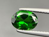 un gros plan sur une tourmaline verte tenue par une paire de pinces