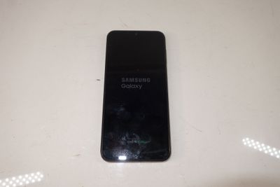 a black samsung phone sitting on a white table