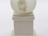 a snow globe with a hand in it on a pedestal