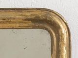 a mirror with a gold frame hanging on a wall