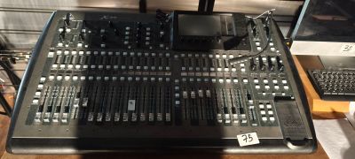 une photo montrant une grande console de mixage posée sur une table en bois