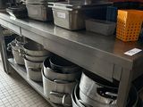 pots and pans are lined up on a metal shelf in a kitchen