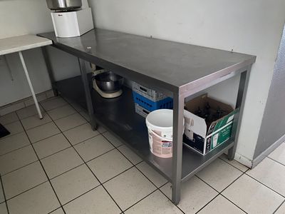 une cuisine avec une table et un seau posé par terre