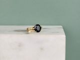 une bague en diamant noir posée sur un bloc de marbre blanc