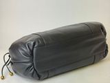 the large black leather bag is sitting on a white surface