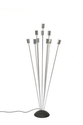 Lampadaire en métal brossé posant sur une base circulaire la…