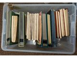 beaucoup de livres dans une boîte en plastique posée par terre