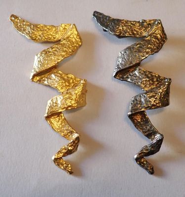trois morceaux de feuille d'or et d'argent sur un fond blanc