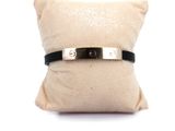 black leather bracelet with a silver clasp on a white pillow