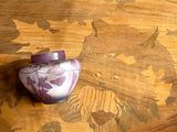 un petit vase violet posé sur une table en bois