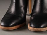 pair of black leather boots with wooden soles on a gray surface