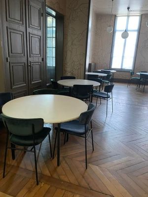 des tables et des chaises dans une pièce dotée d'un parquet et de grandes fenêtres