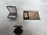 une petite boîte de maquillage et un poudrier posés sur une table