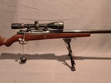 un vieux fusil avec une lunette de visée sur un support sur fond blanc