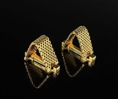two pairs of gold earrings on a black surface